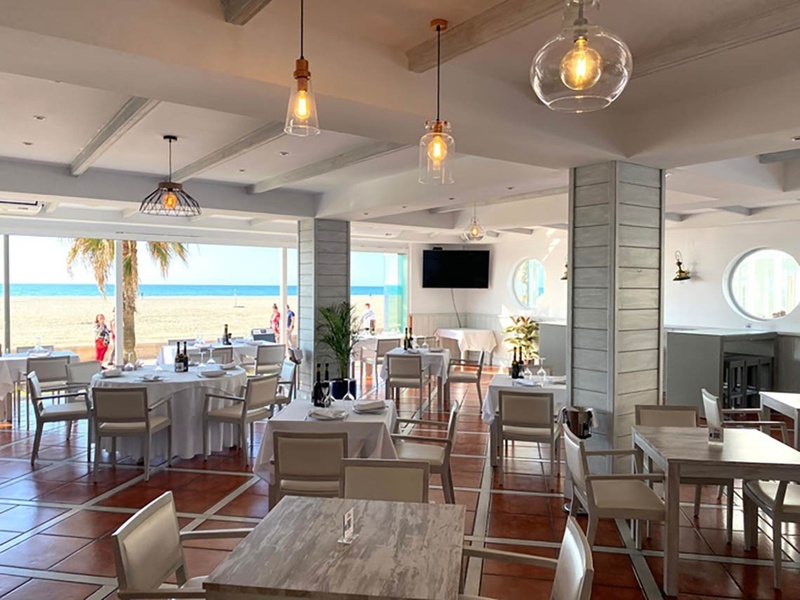 un restaurante con mesas y sillas y una vista al mar