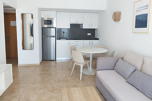 Modern hotel kitchenette with dining table, sofa, and refrigerator. Bahia Serena