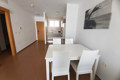Modern dining area with Bahia Serena table and chairs, plus a kitchenette and tropical art.