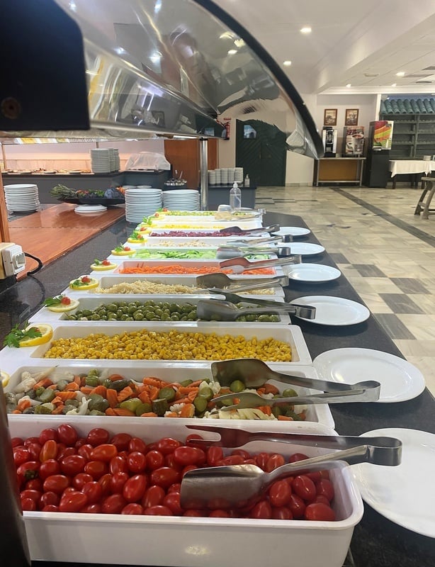un buffet lleno de verduras y platos blancos