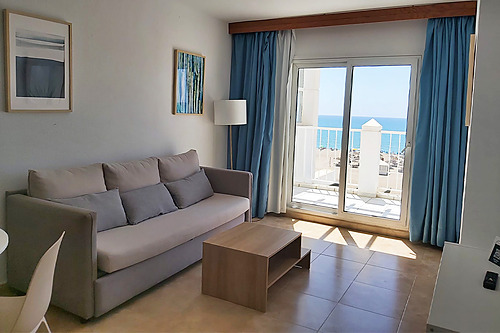 Living room with sofa, coffee table, and sea view balcony in a Bahia Serena.