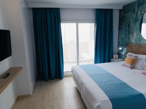 a hotel room with a king size bed and blue curtains