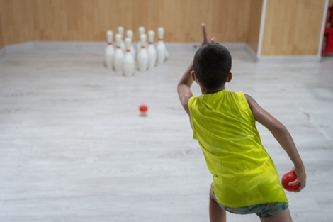 un niño lanza una bola de bolos a los bolos