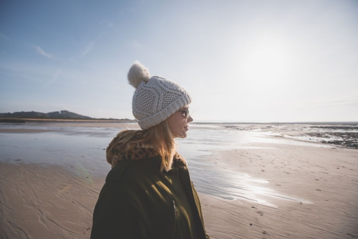 uma mulher com um chapéu branco está de pé na praia