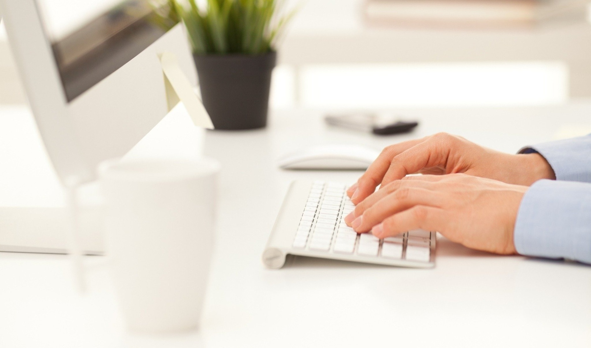 una persona está escribiendo en un teclado frente a una computadora