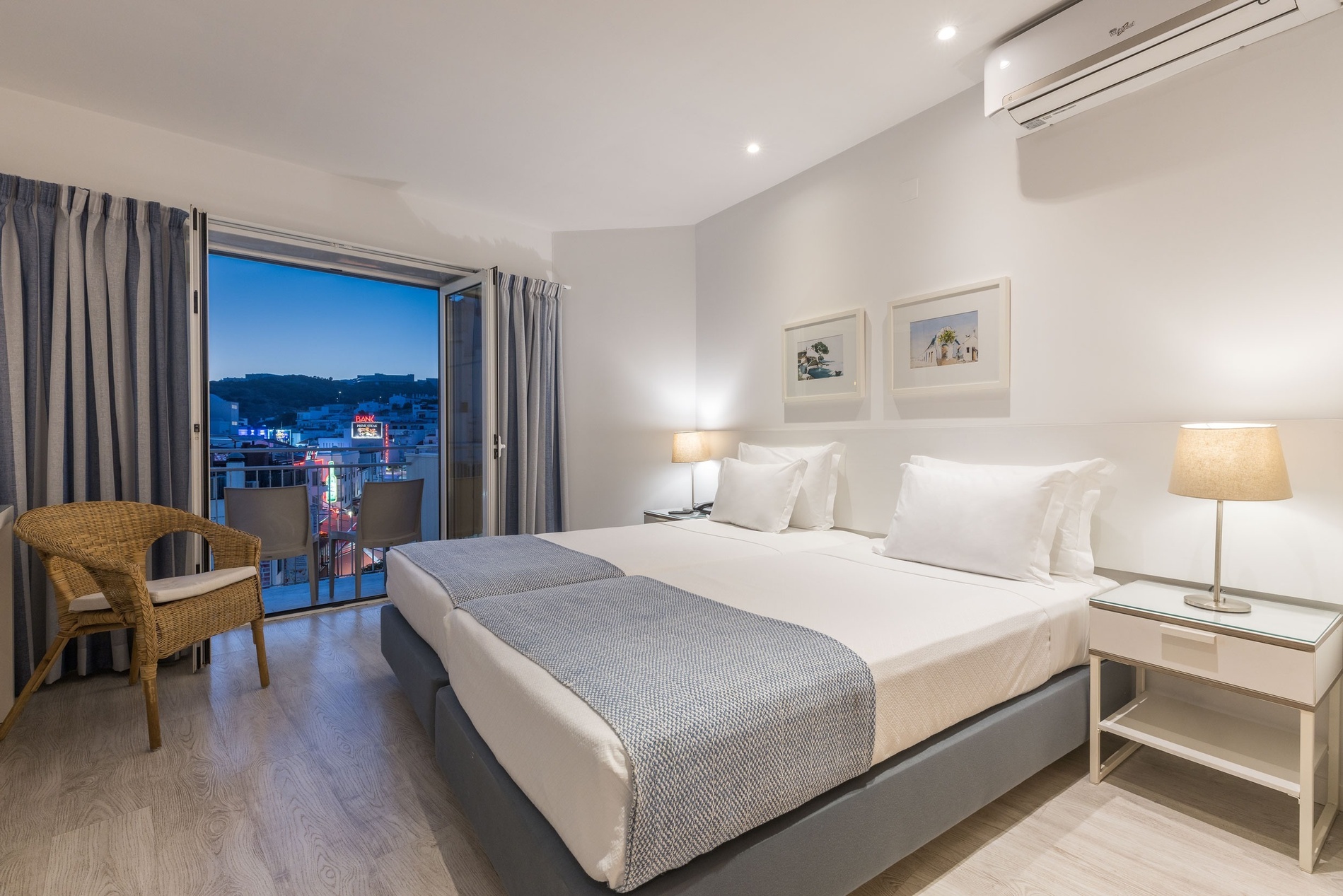 a hotel room with two beds and a wicker chair