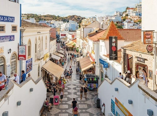 uma rua cheia de pessoas com um restaurante ao fundo