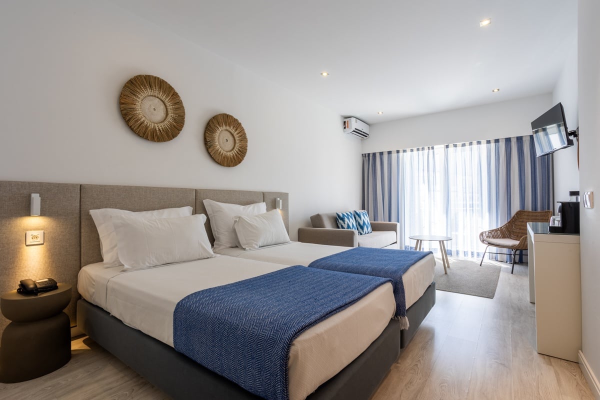 Hotel Baltum: Bright twin room with blue throws, sofa, and balcony view.