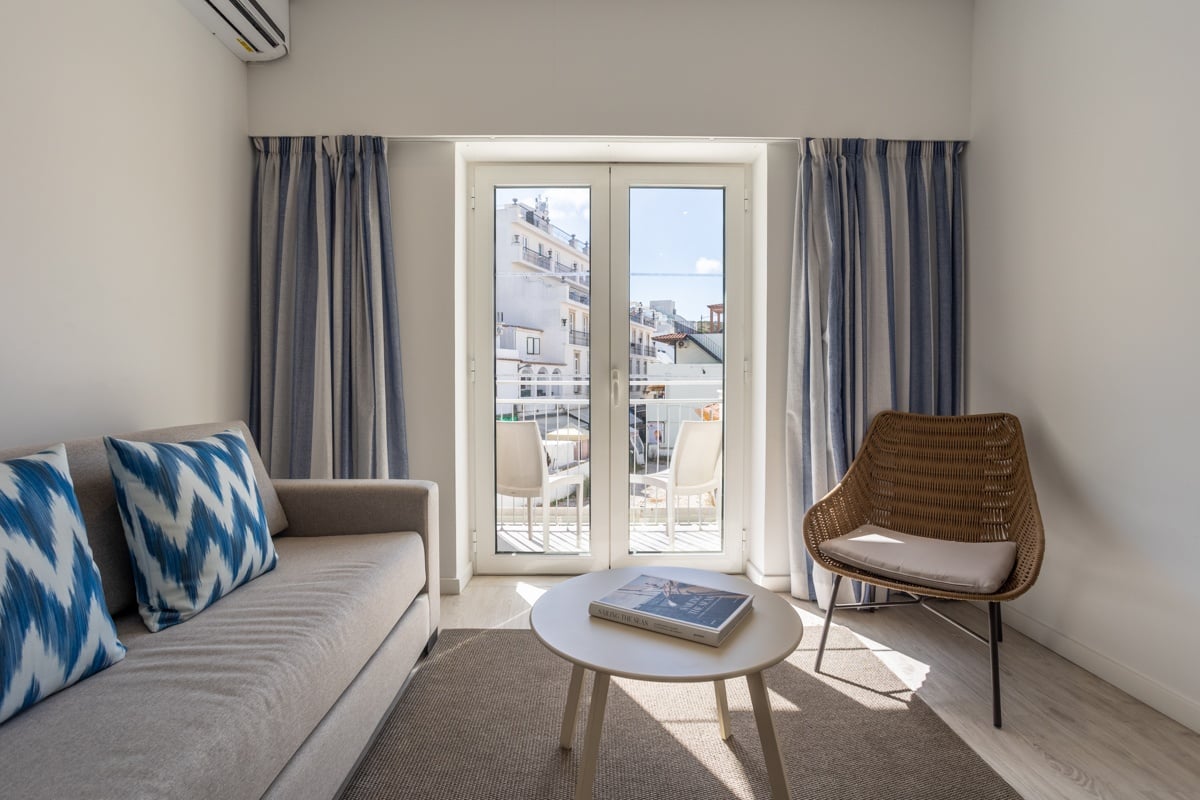 Hotel Baltum room: Cozy seating area with sofa, armchair, coffee table, and balcony view.