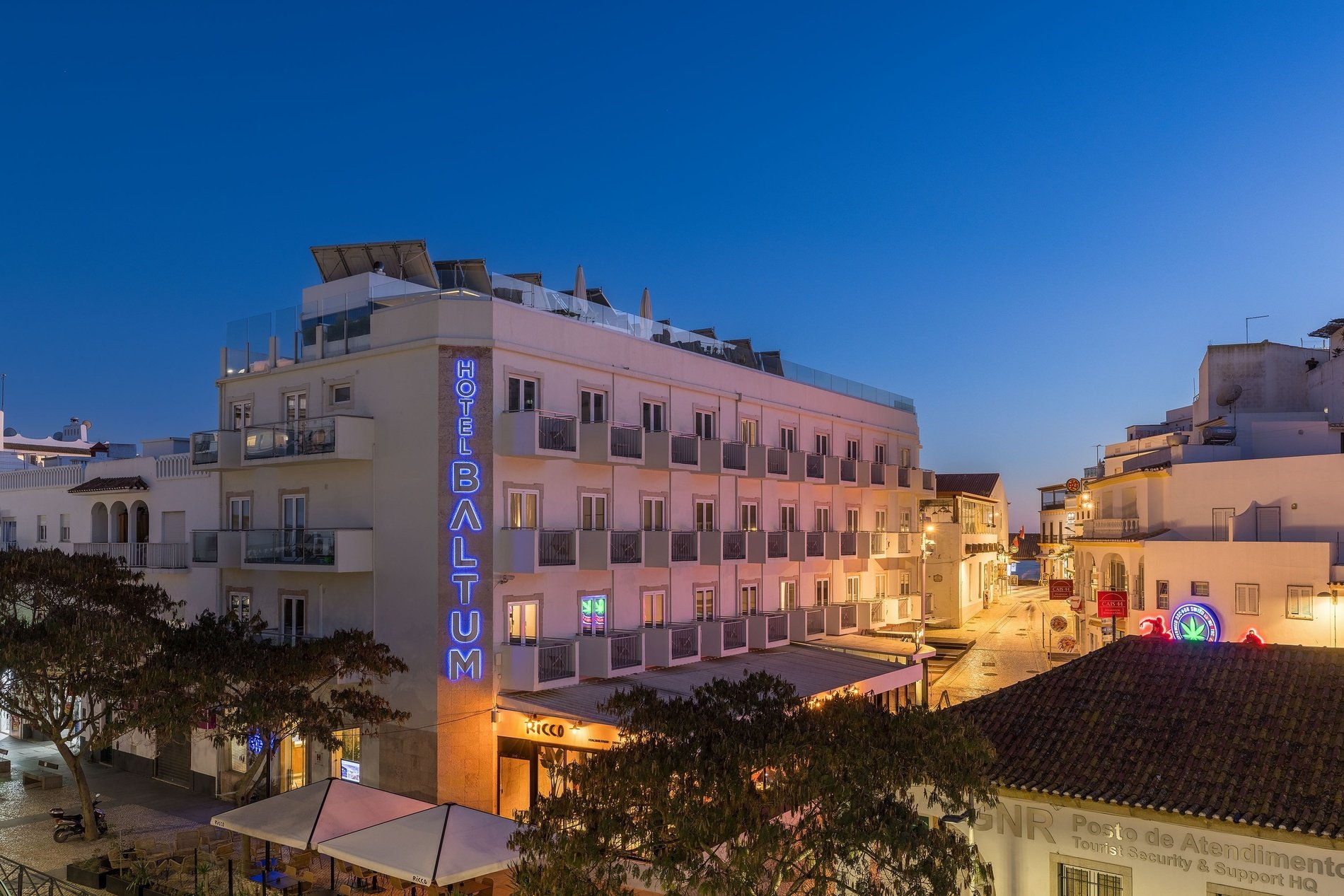 um prédio branco com a palavra hotel baltum em neon azul