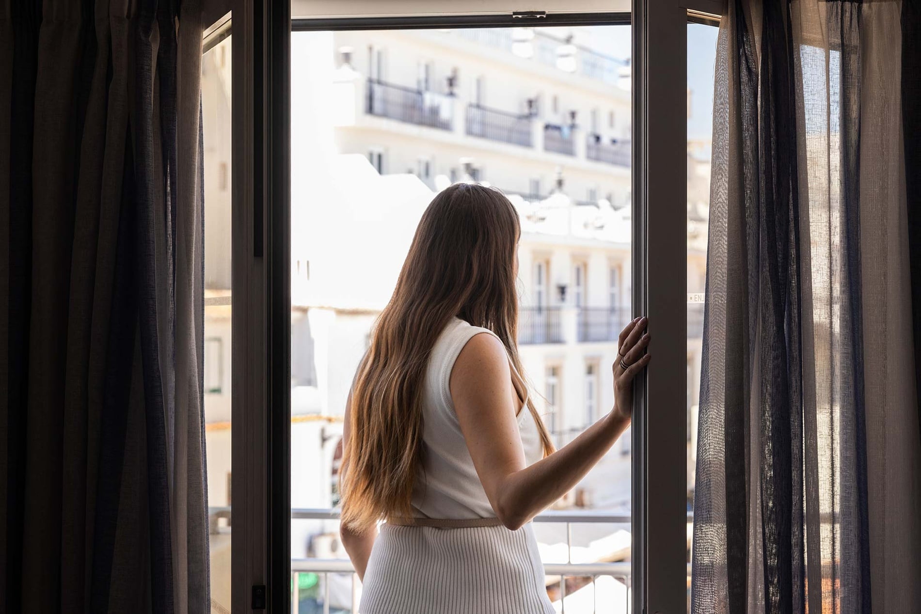 um quarto com cama e cadeira com vista para uma cidade