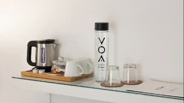 una mesa con una botella de agua , tazas y una tetera .