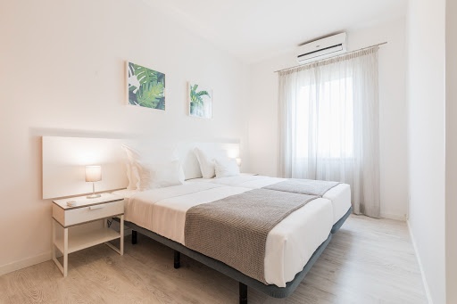 Habitación doble en Baltum con dos camas individuales, mesita de noche y cuadros de hojas verdes.