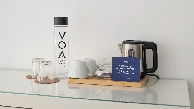 a hotel room with a bottle of water , cups , and a kettle .