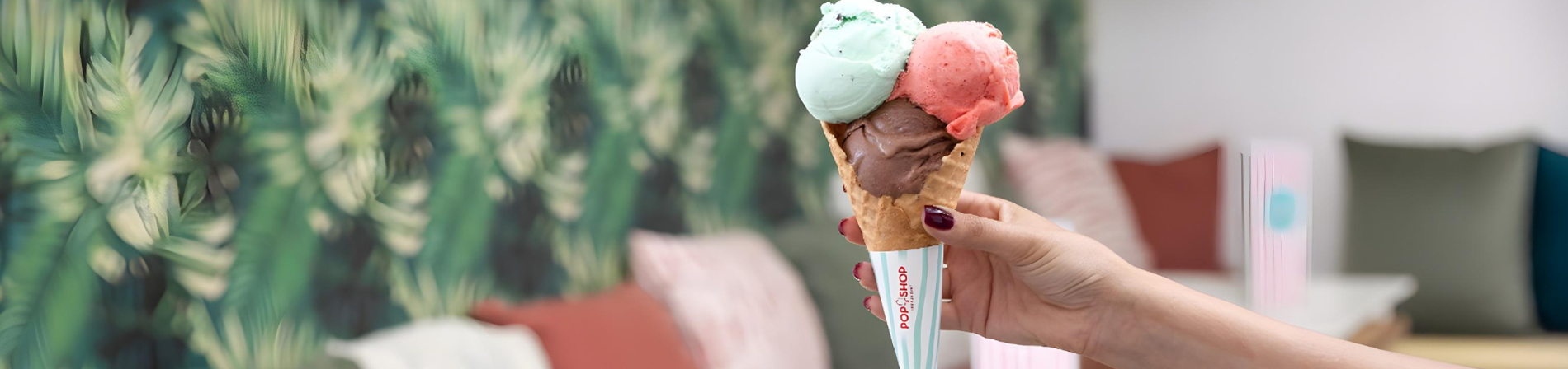 a person holding an ice cream cone that says pop shop on it