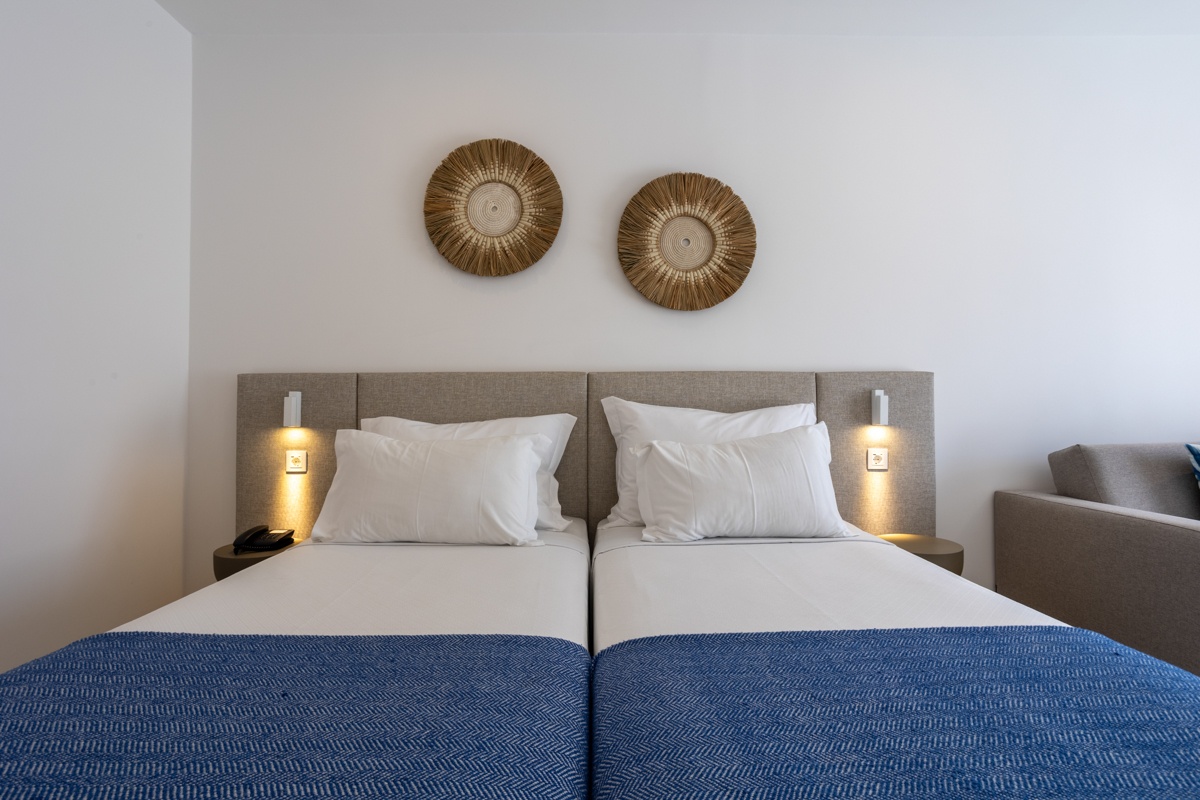 Hotel Baltum | Rooms: Two twin beds with white linens and blue throws, bedside lamps, and woven wall art.