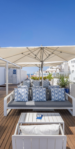 a rooftop deck with a couch and umbrellas