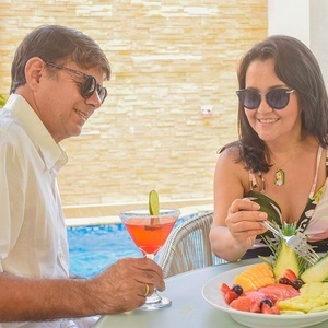 a man and a woman sit at a table with drinks and fruit