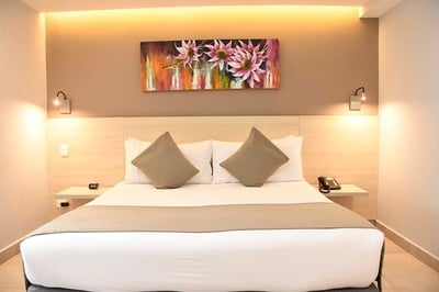 una habitación de hotel con una cama y una pintura de flores en la pared