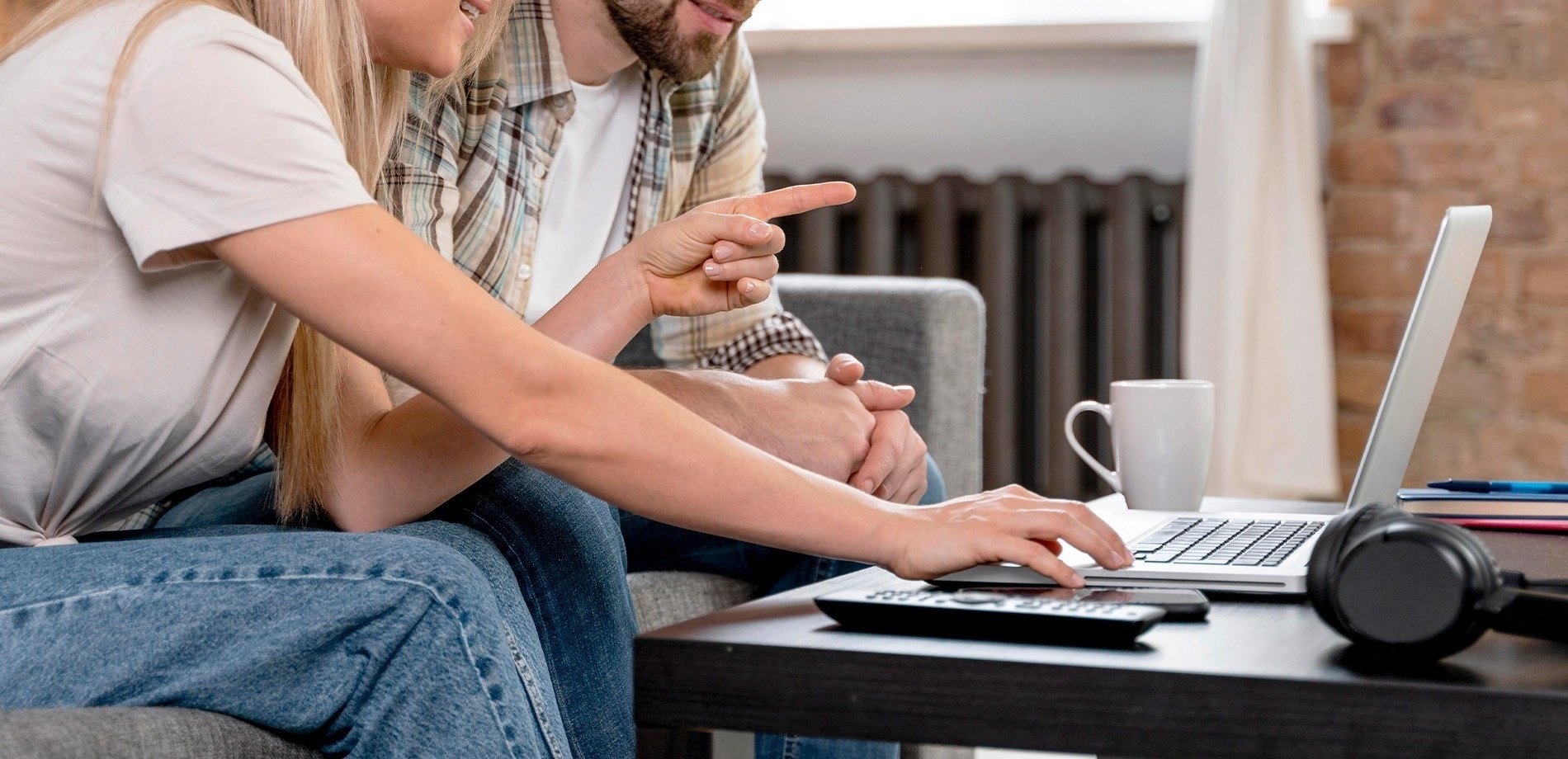 un hombre y una mujer están sentados en un sofá mirando una computadora portátil