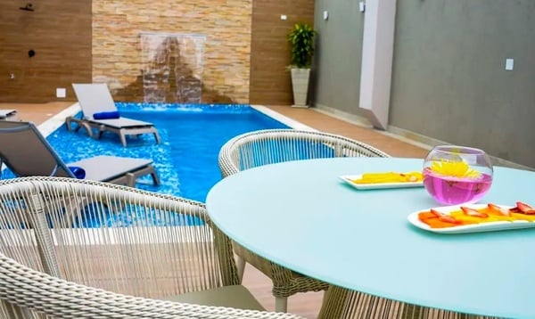 una mesa y sillas frente a una piscina con una cascada