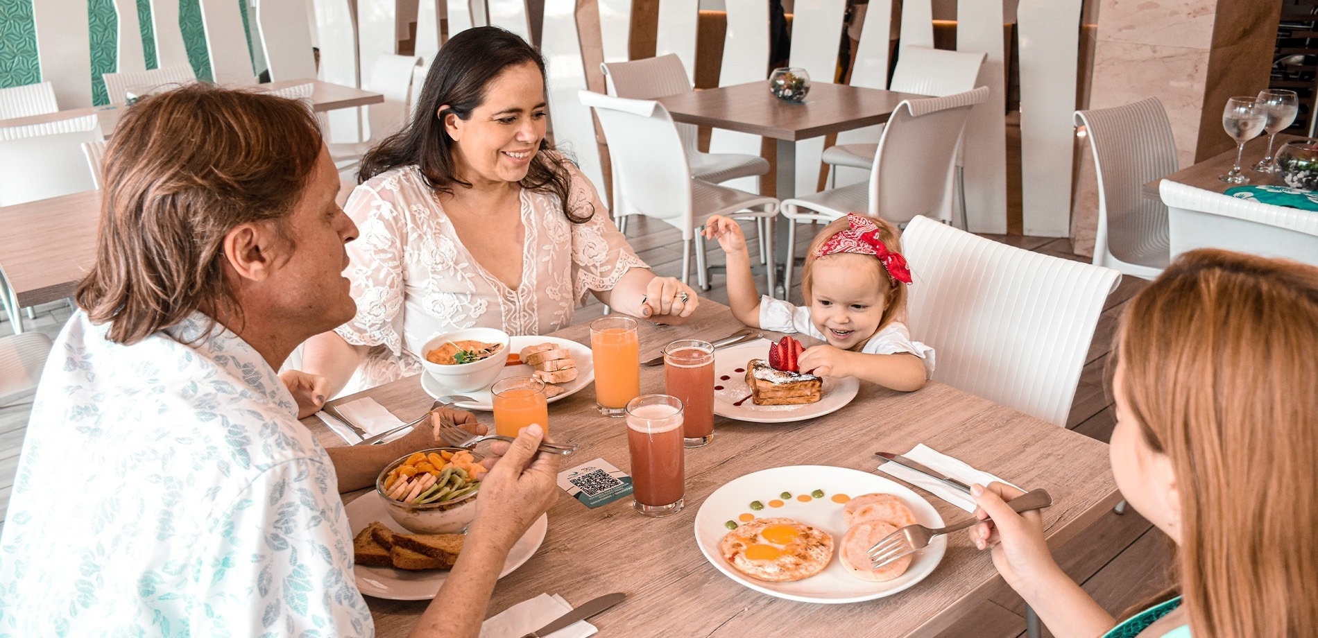 a family sits at a table with plates of food and drinks