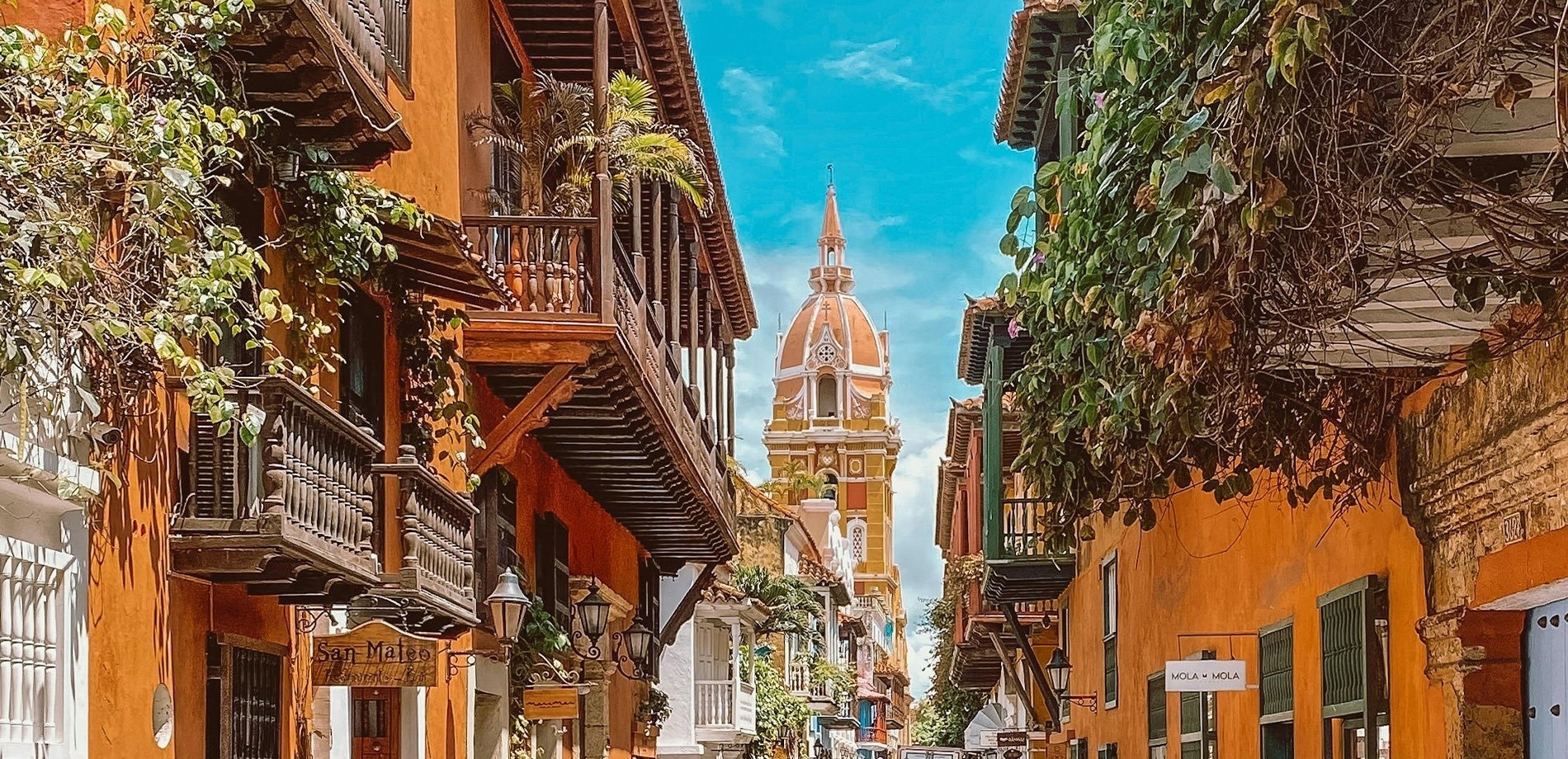 una calle estrecha con edificios amarillos y una iglesia en el fondo