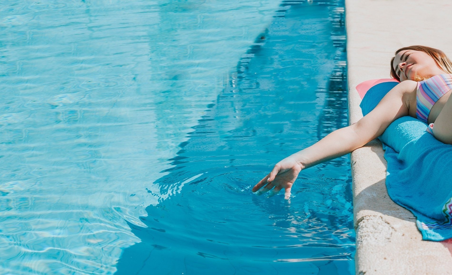 una mujer se sienta en la orilla de una piscina