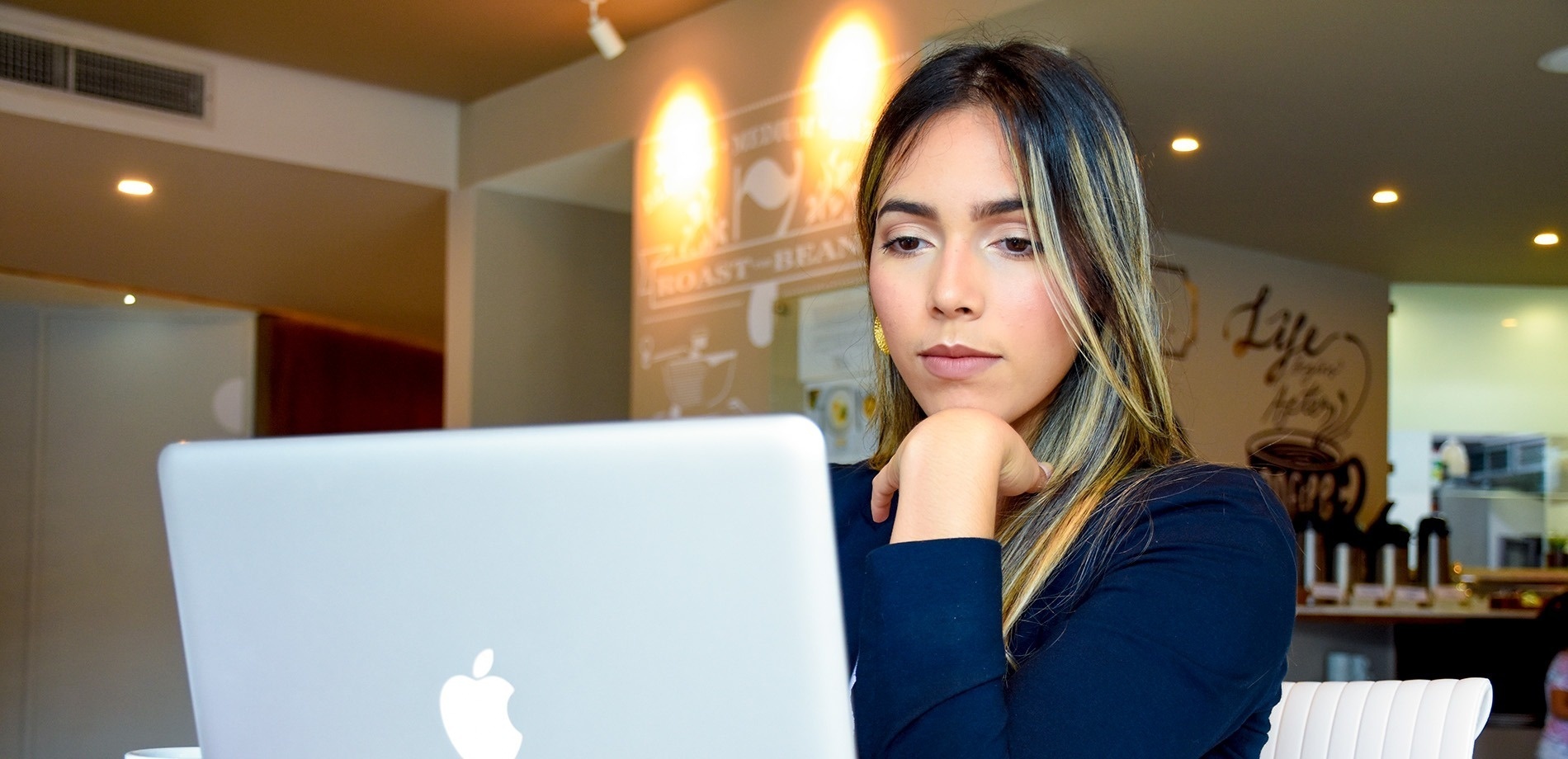 una mujer se sienta frente a una computadora portátil en una cafetería