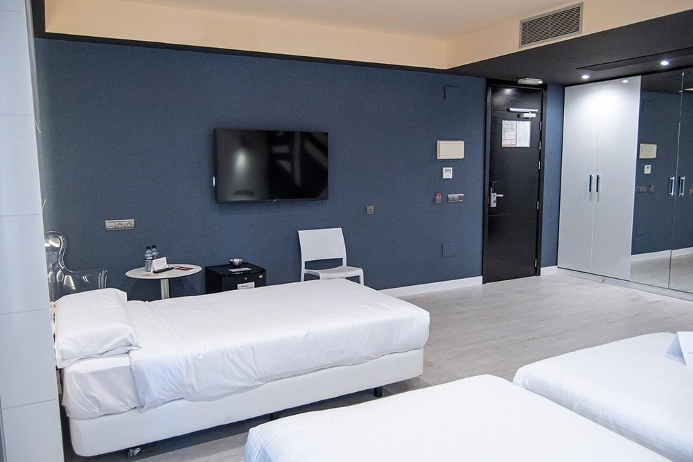 a hotel room with two beds and a flat screen tv
