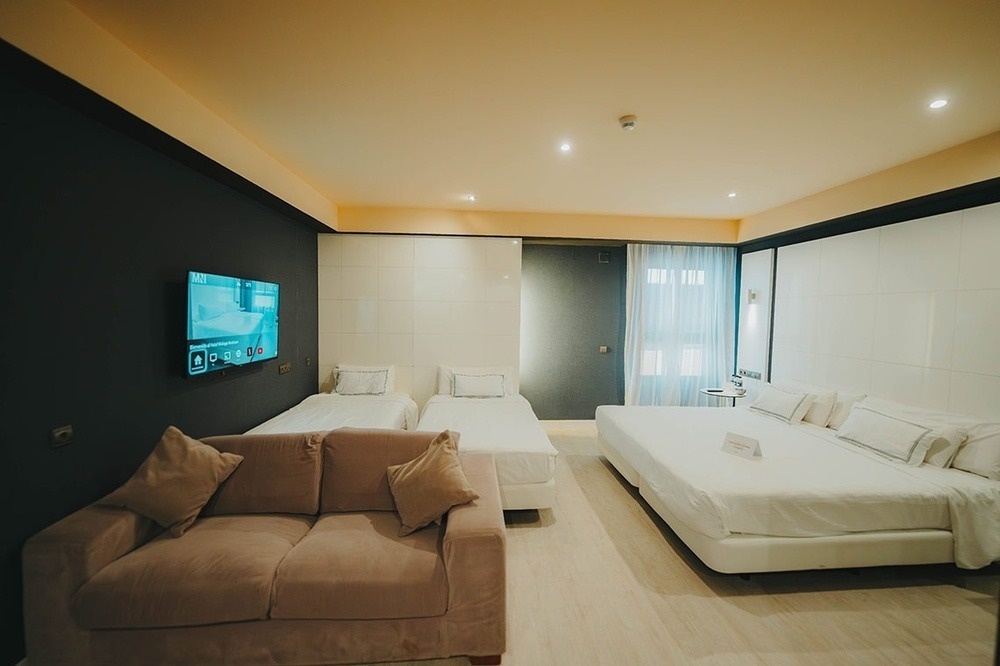 a hotel room with three beds and a flat screen tv