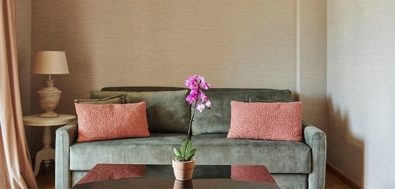 a living room with a green couch and pink pillows