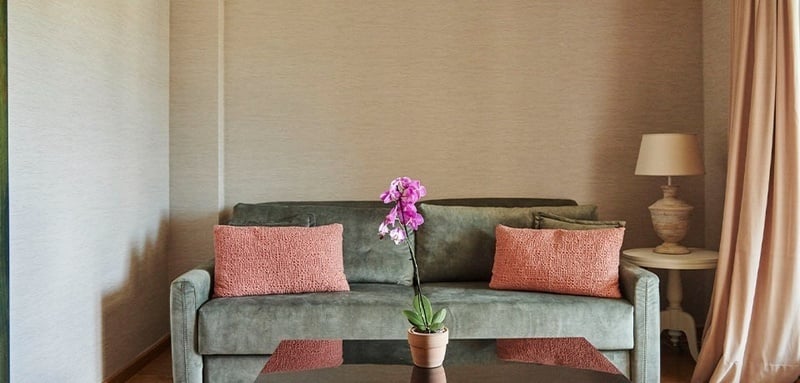 a living room with a green couch and pink pillows