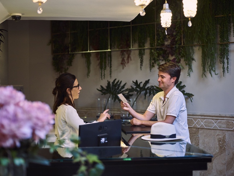 B bou: la vinuela. Smiling receptionist assisting a hotel guest.