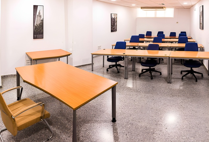 una sala de conferencias con mesas y sillas y una pantalla