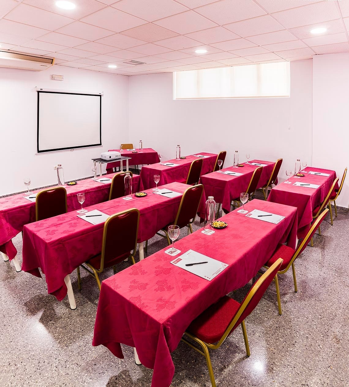 une salle de conférence avec des tables et des chaises et un projecteur