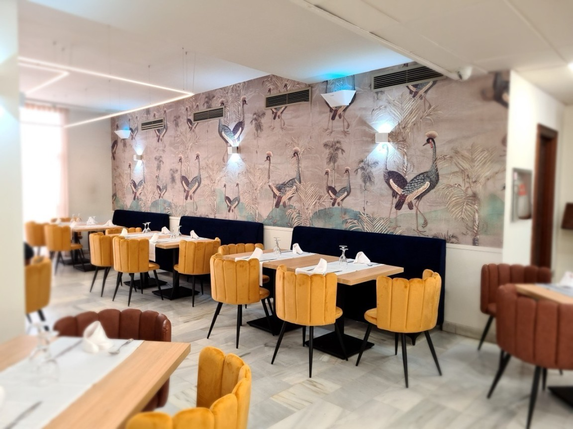 a restaurant with tables and chairs and a wall with birds on it