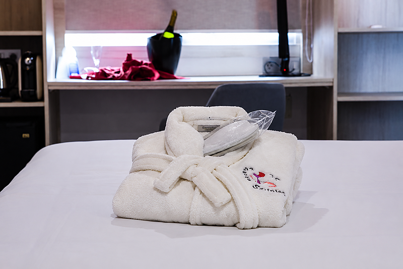 Morbido accappatoio bianco sul letto dell'Hotel Bellavista.