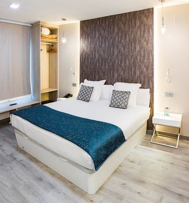 a bed with a blue blanket and pillows in a hotel room