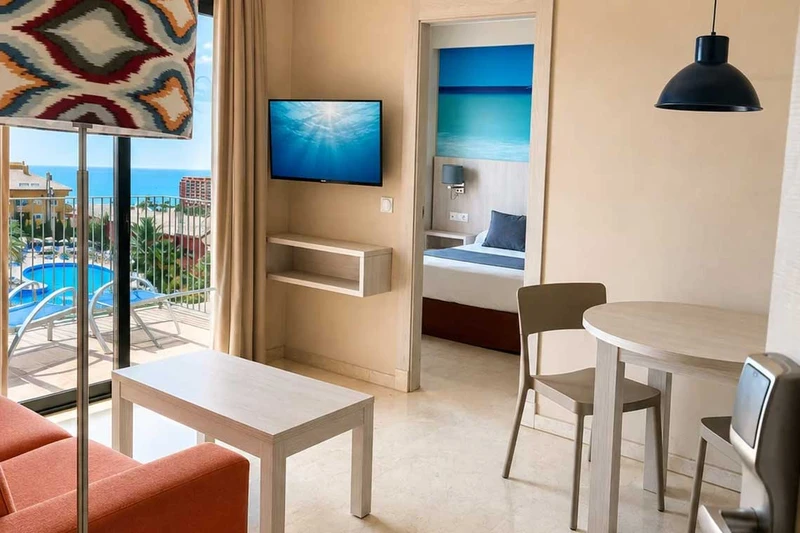 Habitación con balcón y vistas al mar, TV, mesa y acceso a dormitorio. Hotel Spa Benalmádena Palace
