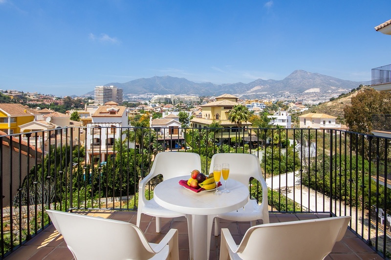 a balcony with a table and chairs and mountains in the background