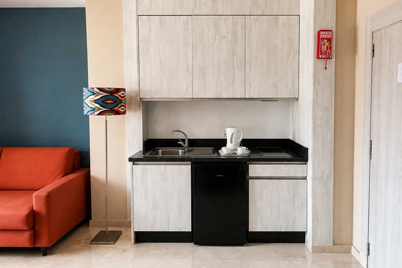 Cocina moderna de hotel con sofá naranja y lámparaHotel Spa Benalmádena Palace.