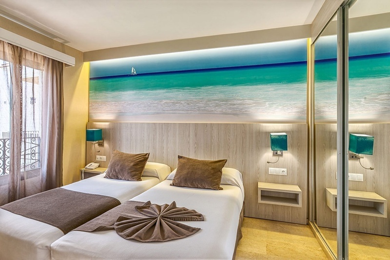 a hotel room with two beds and a picture of the ocean on the wall