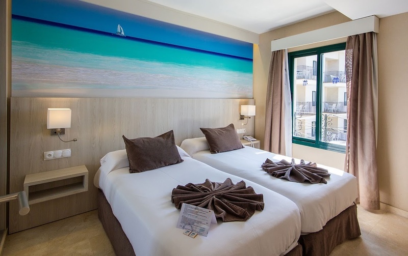 a hotel room with two beds and a sailboat on the wall