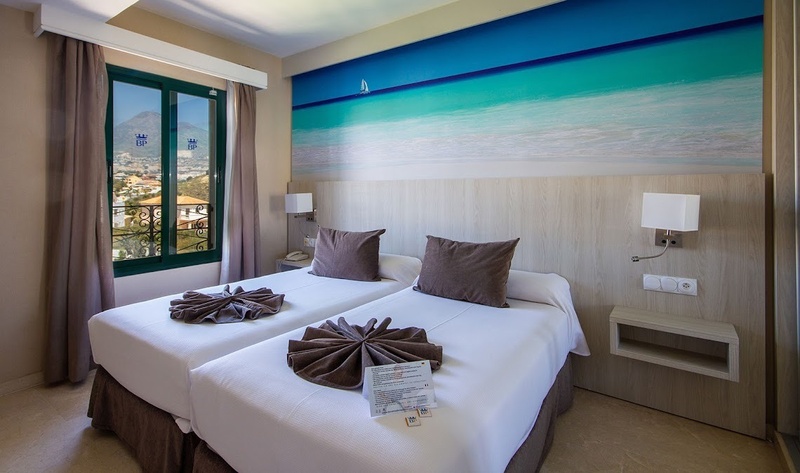 een hotelkamer met twee bedden en een schilderij van de oceaan op de muur