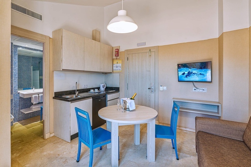 een kleine keuken met een tafel en stoelen en een televisie aan de muur