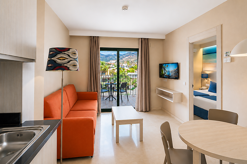 Woonkamer met oranje bank, eethoek en balkon in het Benalmádena Palace