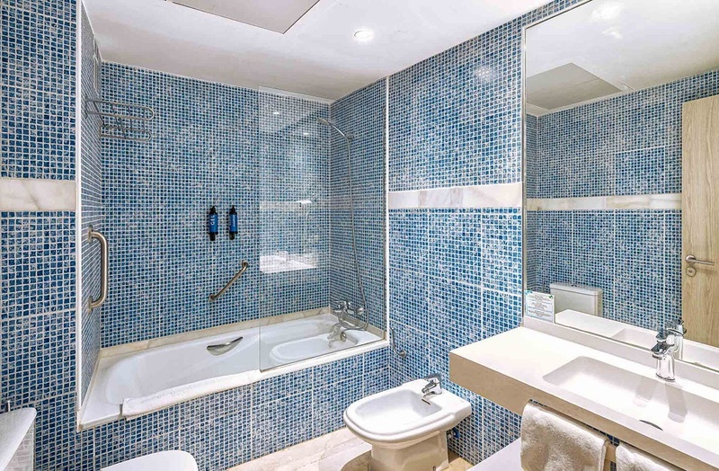 a bathroom with blue tiles and a bathtub