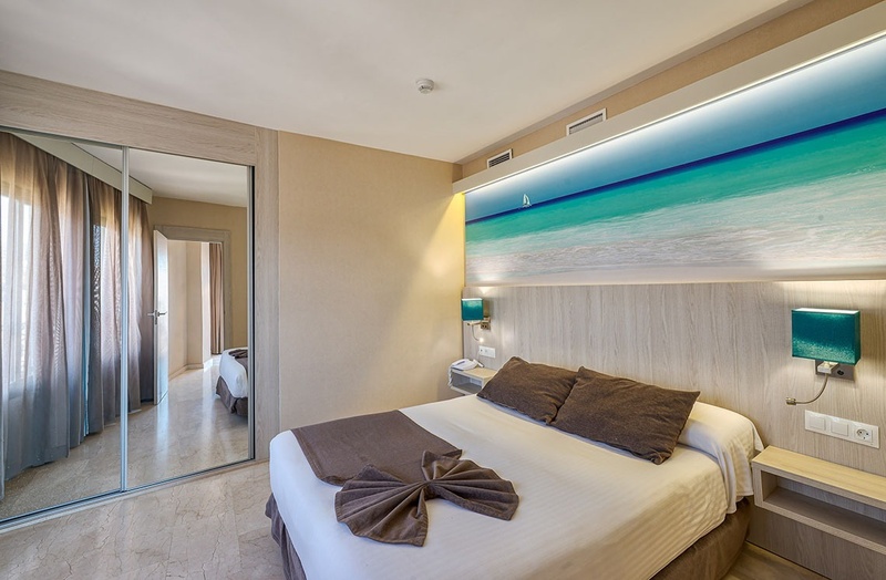 a hotel room with a large picture of the ocean on the wall above the bed