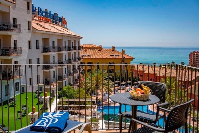 a balcony with a table and chairs in front of a building that says belmonte